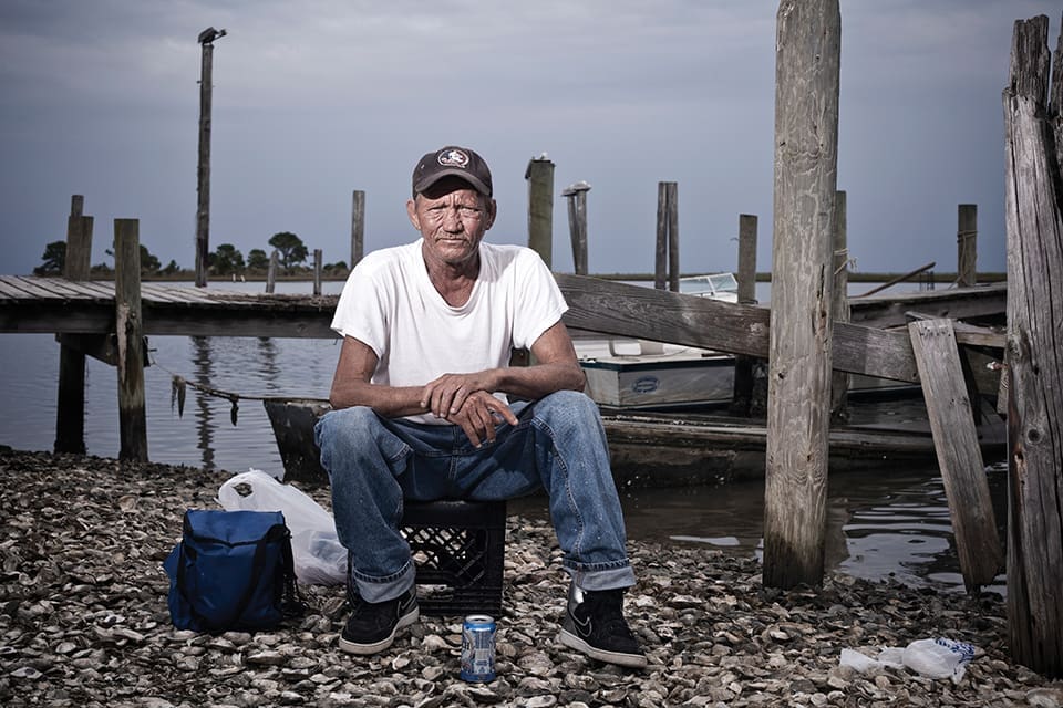 Where Have All the Oysters Gone? 2 Carl Sanders, 52, sits on the shore of the Apalachicola Bay after a day of catching oysters. He has been an oysterman his entire life. (Photo by Jeremiah Stanley)