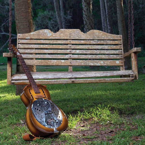 JJ Grey's Dobro guitar leans against a wooden tree swing that looks like an old bench.