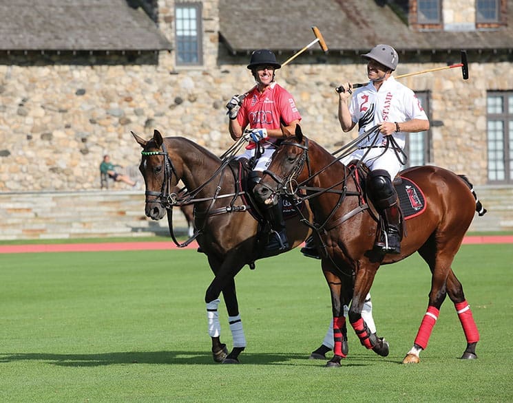 Brandon Phillips looks at friend and fellow player Nic Roldan at the Greenwich Polo Club. They are both smiling, and it is bright. They have their gear on.