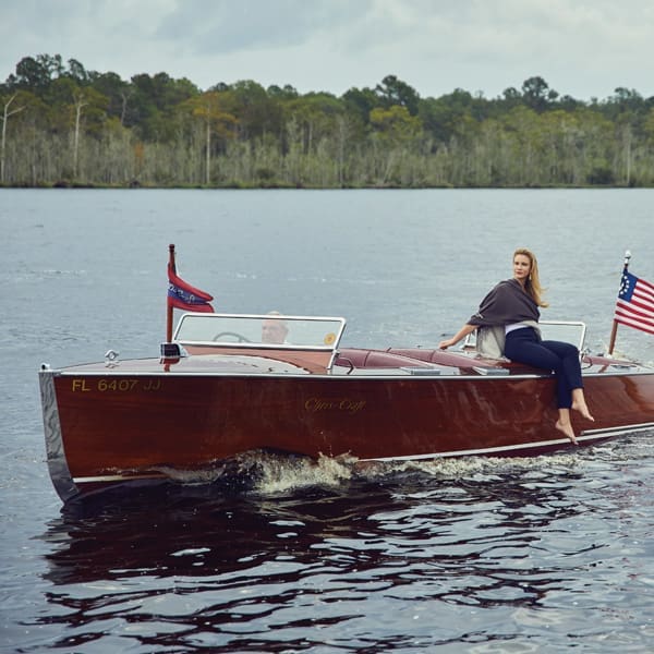 A model poses on the Chris-Craft a shiny, wooden boat. 