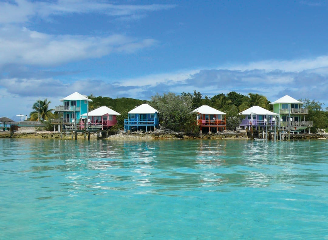 Colorful cottages on stilts are nestled in the shoreline and reflected into the rippling water.