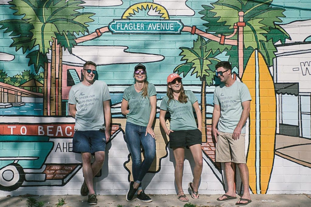 Small business owners standing in front of a mural.