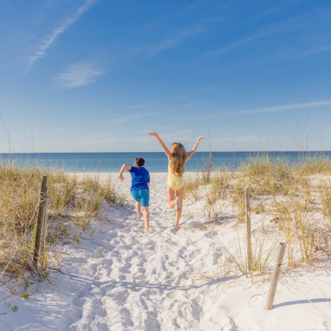 Young children run down to the beach.