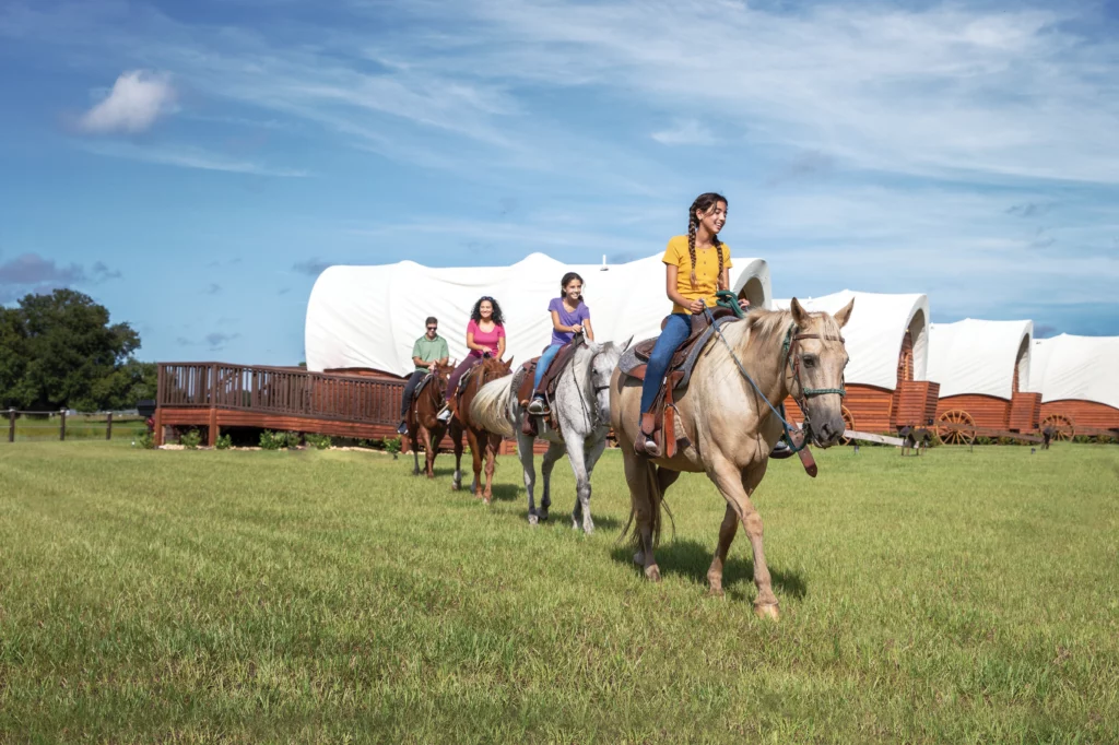 Four guests ride horseback past Westgate River Ranch's glamping tents.