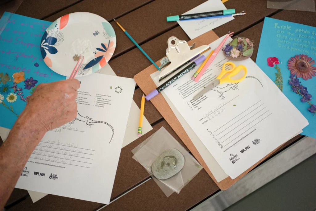 Markers and dried flowers surround Ode to Boca prompts