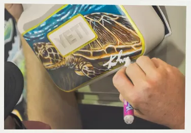 The Homegrown Holiday Edit: 2025 Gift Guide 15 Artist Travis Luther painting a nature scene on to a Yeti Sidekick.